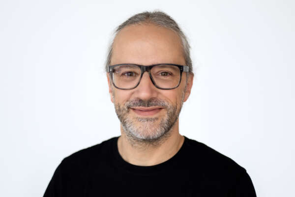 Portrait von Markus Fertig, der ein schwarzes Shirt trägt und in die Kamera lächelt 