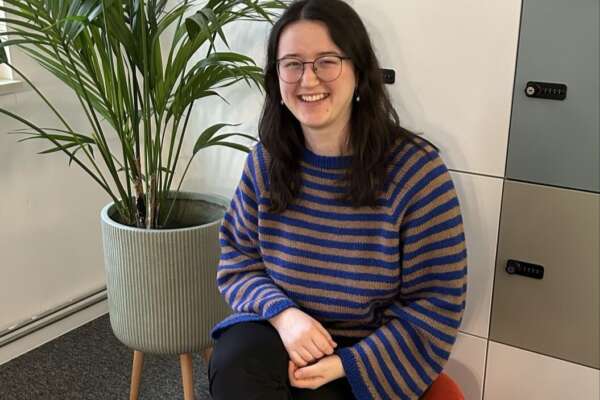 Franziska Werum sitzt auf einem Hocker neben einer Topfpflanze