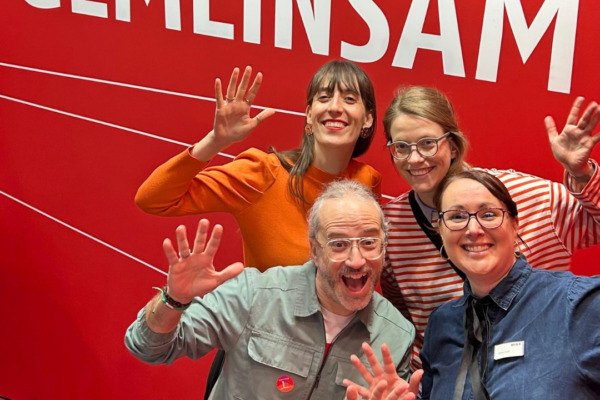 Markus, Rahel, Angie und Katrin stehen vor dem Schriftzug "Gemeinsam"